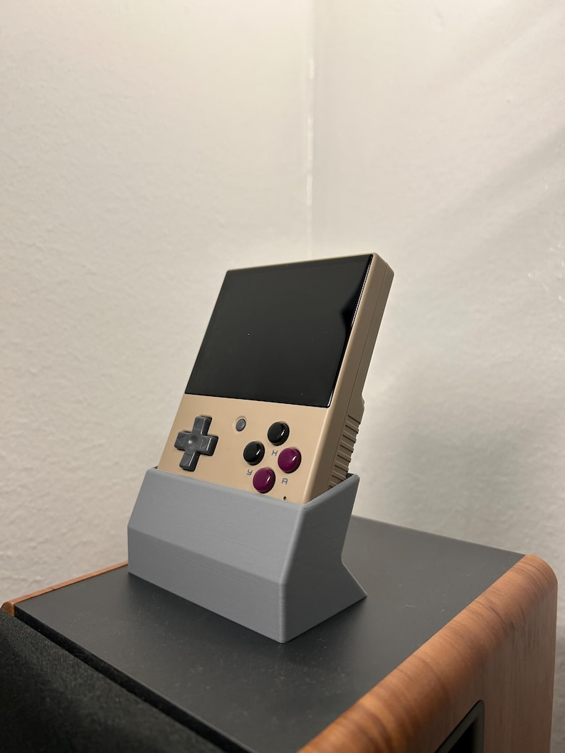 Miyoo Mini plus handheld gaming device shown in the gray dock, showing the aesthetic angle from the side.