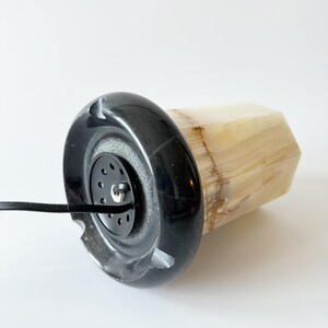 May include: A black and white onyx lamp with a black cord. The lamp has a round base and a hexagonal body.