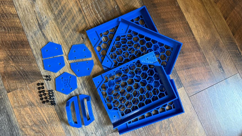 Puede incluir: Un conjunto de piezas impresas en 3D de color azul para una caja de ordenador. Las piezas incluyen un panel en forma de panal, un panel rectangular y varias piezas m&aacute;s peque&ntilde;as. Tambi&eacute;n se incluyen peque&ntilde;os tornillos negros.