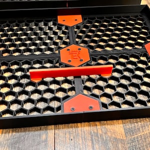 Puede incluir: Bandeja negra y naranja con patr&oacute;n de panal de abeja, con asas de pl&aacute;stico rojo y una etiqueta negra que dice "SOMO" en letras blancas.