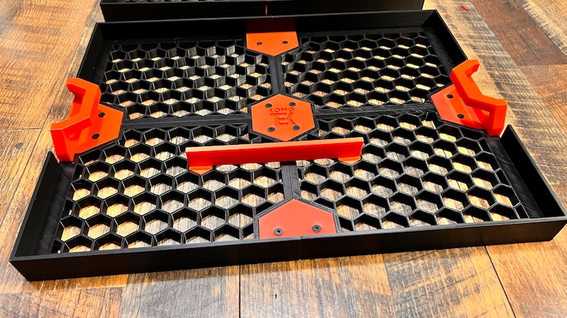 Puede incluir: Bandeja negra y naranja con patr&oacute;n de panal de abeja, con asas de pl&aacute;stico rojo y una etiqueta negra que dice "SOMO" en letras blancas.