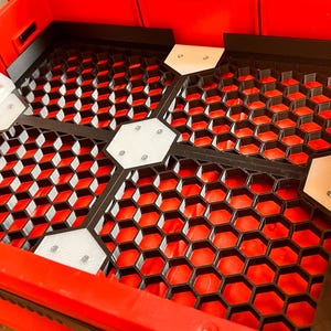 Puede incluir: Contenedor de almacenamiento de pl&aacute;stico rojo con un inserto de rejilla de panal negro y divisores de pl&aacute;stico blanco. Los divisores tienen peque&ntilde;as asas de pl&aacute;stico blanco.