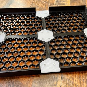 Puede incluir: Cuatro baldosas cuadradas negras con un patr&oacute;n de panal y conectores de pl&aacute;stico blanco. Las baldosas est&aacute;n dispuestas en forma de cuadrado.