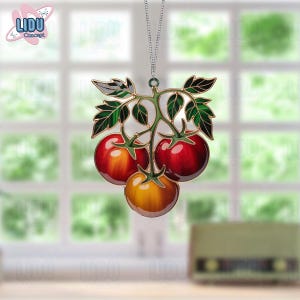 Peut inclure: Ornement décoratif représentant une grappe de tomates. Les tomates sont rouges et oranges, avec des feuilles et des tiges vertes. L'ornement est suspendu à une chaîne argentée. Le logo "LIDU Concept" est visible en haut à gauche.