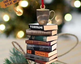 May include: A personalized Christmas ornament featuring a stack of books with a coffee mug on top. The mug has a galaxy design and the top book has the text "YOURNAME" printed on it.