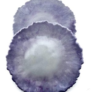 May include: Two purple and gray resin coasters with a scalloped edge.