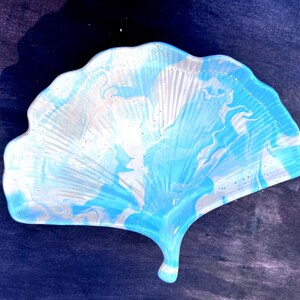 May include: A blue and white ginkgo leaf-shaped dish with a marbled design. The dish is made of resin and has a glossy finish.