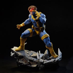May include: A detailed figurine of Cyclops from the X-Men, in a dynamic pose. The figure is clad in a blue and yellow costume, with a red visor. The base is a detailed, rocky terrain. The overall aesthetic is comic book style.