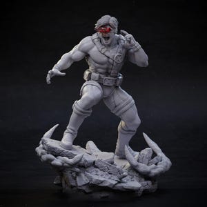 May include: A gray, 3D-printed figurine of a muscular superhero in a dynamic pose. The figure wears a costume with straps and a belt, and has a red visor. The base is a rocky terrain.