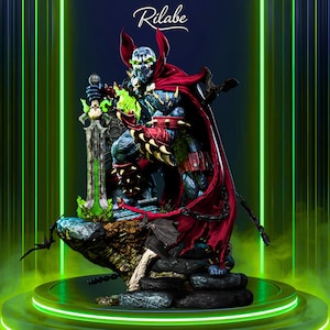 Puede incluir: Estatua detallada de Spawn, un personaje de cómic, sobre una base rocosa. La figura viste un traje azul y negro con capa y guanteletes rojos. Sostiene una espada verde brillante. Se ve el logo "Rilabe".