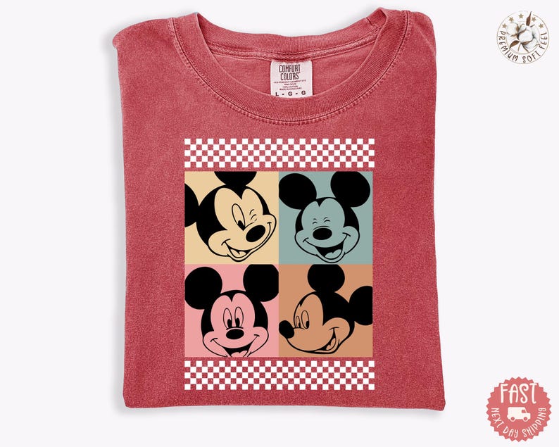 Peut inclure: T-shirt rouge avec un motif de style pop art repr&eacute;sentant le visage de Mickey Mouse en quatre expressions diff&eacute;rentes. Le motif est encadr&eacute; d'un motif &agrave; carreaux. Le t-shirt a un col rond et des manches courtes.