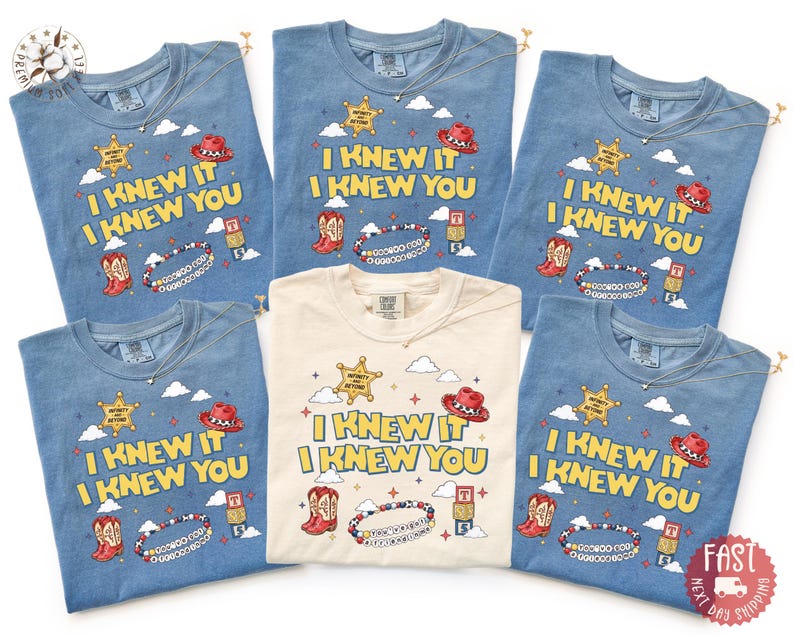 May include: Five t-shirts in blue and cream colors featuring the text I KNEW IT I KNEW YOU. The graphic includes a sheriff star, a red cowboy hat, cowboy boots, a beaded bracelet, and building blocks with the letters T and S against white clouds.