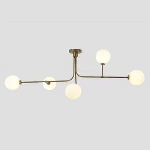Pode incluir: Uma moderna luminária de teto com acabamento em bronze e cinco cúpulas esféricas de vidro fosco. A luz tem um design minimalista com uma haste central e braços horizontais que se estendem para fora, cada um segurando uma luz.