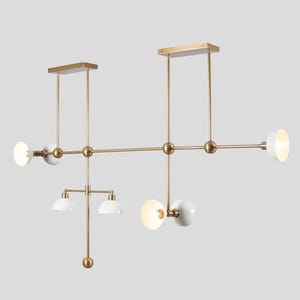 May include: A modern gold and white chandelier with multiple light bulbs. The chandelier has a geometric design with a long horizontal bar and several vertical bars.
