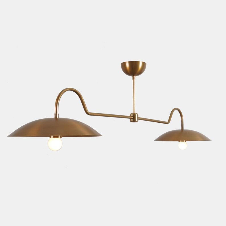 May include: A brass two-light pendant light fixture with curved arms and round shades.