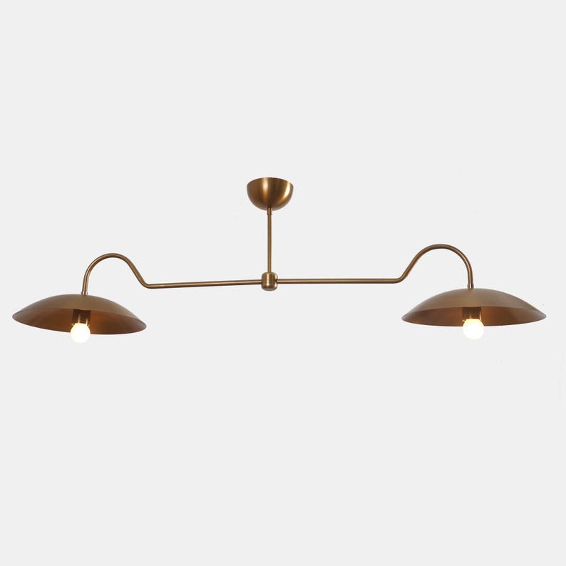 May include: A brass two-light pendant light fixture with curved arms and round shades.