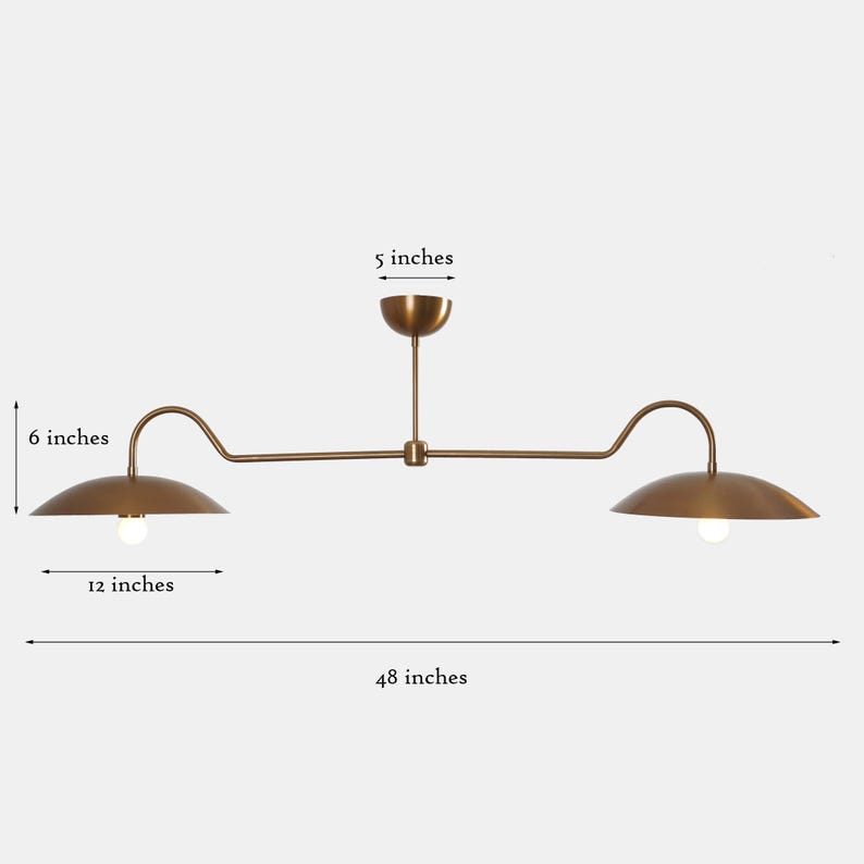 May include: A brass double-headed pendant light fixture with two curved arms. Each arm has a 6-inch diameter shade and the fixture is 48 inches long.