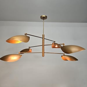 Puede incluir: Una lámpara de araña moderna de latón con cinco pantallas curvas ajustables. La lámpara de araña tiene un diseño elegante y minimalista y sería una adición elegante a cualquier hogar contemporáneo.