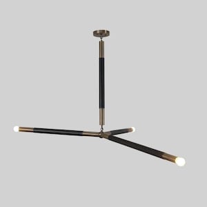May include: A modern black and brass chandelier with three arms extending from a central point. Each arm has a black cylindrical shade with a brass tip and a light bulb at the end.