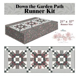 May include: A fabric runner kit with the text "Down the Garden Path Runner Kit." The runner is 21" x 57" and features a floral and geometric pattern in shades of gray, red, and white. The design includes star-shaped blocks and a gingham border.