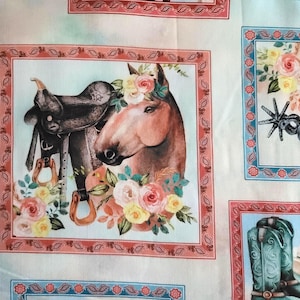 May include: Fabric with a repeating pattern of framed images. One frame features a horse with a saddle and floral accents. Other frames show floral arrangements, cowboy boots, and spurs. The color palette includes pink, blue, and brown.