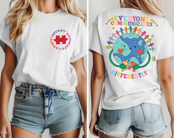 May include: White t-shirt with a colorful graphic on the front that says "Adapt, Accept, Advocate" with a red puzzle piece in the center. The back of the shirt has a colorful graphic of a smiling earth holding a puzzle piece with the text "Everyone Communicates Differently".