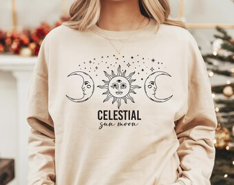 May include: A beige sweatshirt with a black graphic of a sun, moon, and stars. The text "CELESTIAL sun moon" is printed below the graphic.