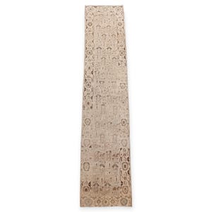 Könnte beinhalten: Ein rechteckiger, beigefarbener Läuferteppich mit einem aufwendigen, sich wiederholenden Muster in Brauntönen. Der Teppich weist ein zentrales Design mit geometrischen Formen und floralen Motiven auf, was eine Vintage-Ästhetik erzeugt. Ideal für Flure oder Eingangsbereiche.