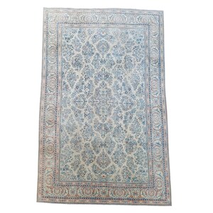 May include: An ivory-colored, rectangular rug with an intricate floral pattern in shades of blue, brown, and red. The rug features a detailed border with repeating motifs. The overall design is symmetrical and traditional.