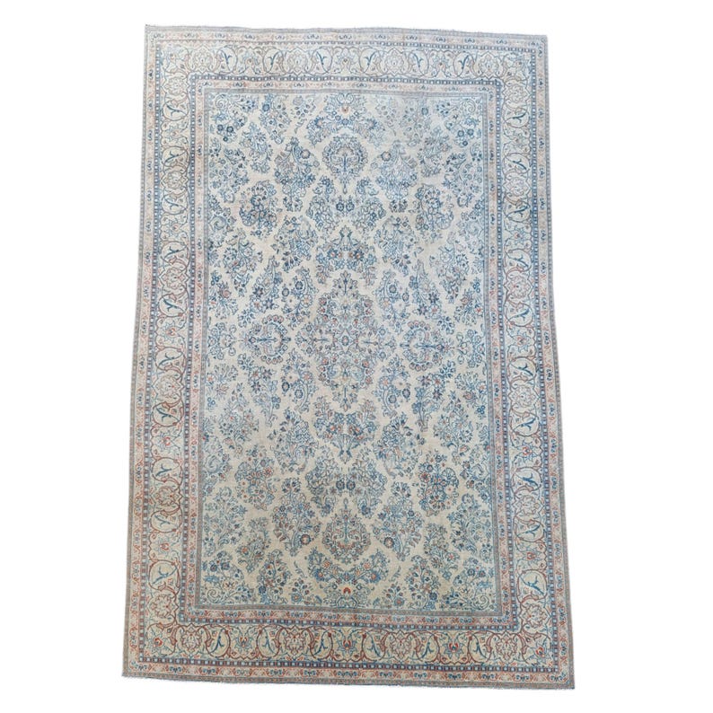 May include: An ivory-colored, rectangular rug with an intricate floral pattern in shades of blue, brown, and red. The rug features a detailed border with repeating motifs. The overall design is symmetrical and traditional.