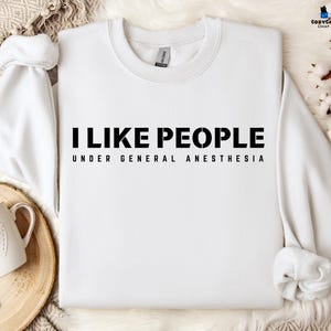 May include: White sweatshirt with black text that reads "I like people under general anesthesia".