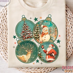 May include: A beige sweatshirt with a vintage Christmas design featuring four baubles. Each bauble depicts a different festive scene: a Christmas tree, a snowman, a reindeer, and Santa Claus.