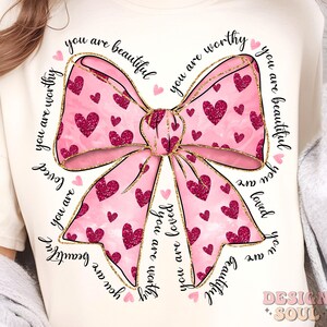May include: A pink and gold bow with a glitter design and the words "you are beautiful you are worthy you are loved you are beautiful you are worthy" surrounding it.