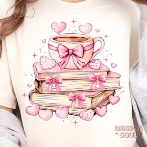 K&ouml;nnte beinhalten: Ein wei&szlig;es T-Shirt mit einer rosa Kaffeetasse, einer rosa Schleife und einem Stapel B&uuml;cher mit rosa Schleifen. Die B&uuml;cher sind von rosa Herzen und Sternen umgeben.