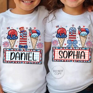 May include: White t-shirts with patriotic ice cream cone and popsicle designs. Each shirt features a name, "DANIEL" and "SOPHIA", in a red and blue plaid frame, with fireworks and stars.