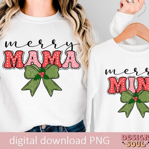 May include: Two white long-sleeve shirts with a Christmas theme. The larger shirt says "merry mama" in pink and red letters with white polka dots and a green bow with holly. The smaller shirt says "merry mini" in pink and red letters with white polka dots and a green bow with holly.
