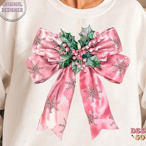 May include: A white sweatshirt with a pink bow and holly design. The bow is decorated with snowflakes and the holly has pink berries.