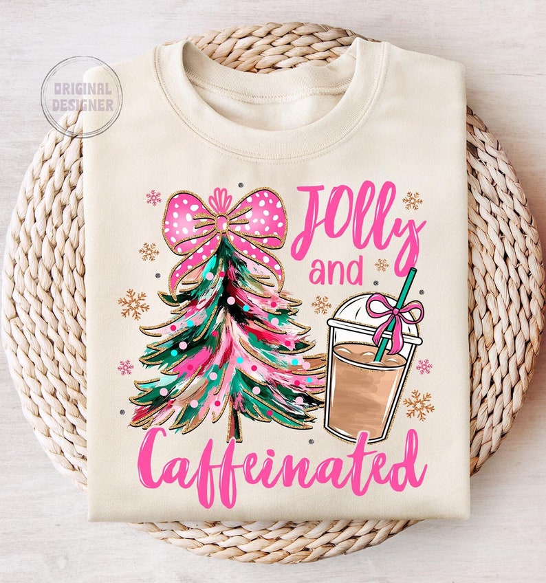 May include: A cream-colored sweatshirt with a pink Christmas tree and a pink bow on top. The text "Jolly and Caffeinated" is written in pink letters.