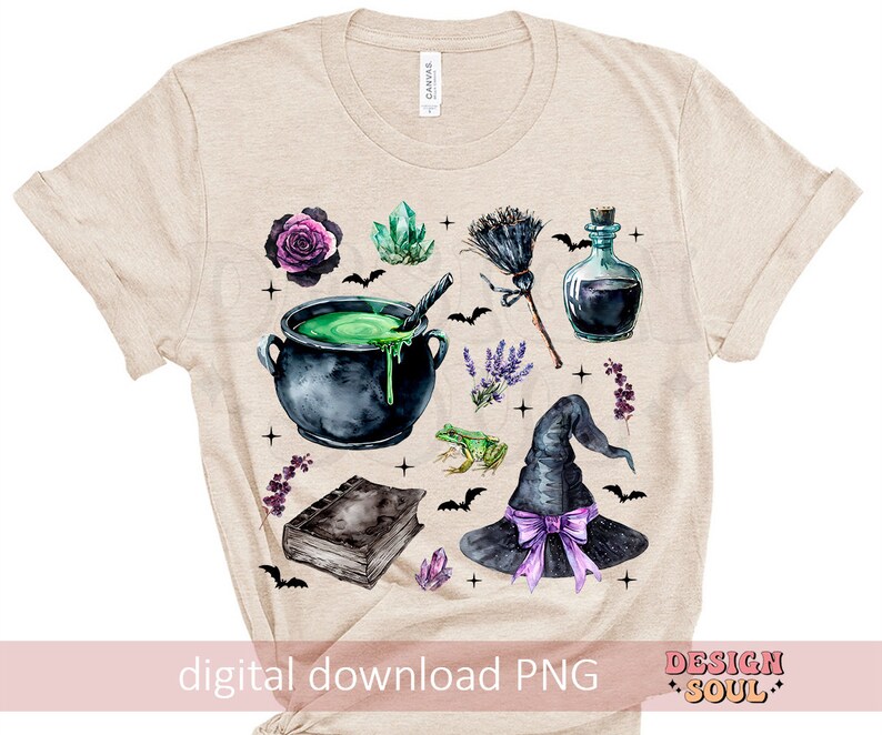 May include: A beige t-shirt with a watercolor design of a witch's cauldron, a witch's hat, a frog, a book, a bottle, a broom, and flowers. The design is in shades of green, purple, black, and brown.