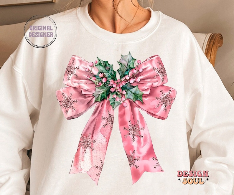 May include: A white sweatshirt with a pink bow and holly design. The bow is decorated with snowflakes and the holly has pink berries.