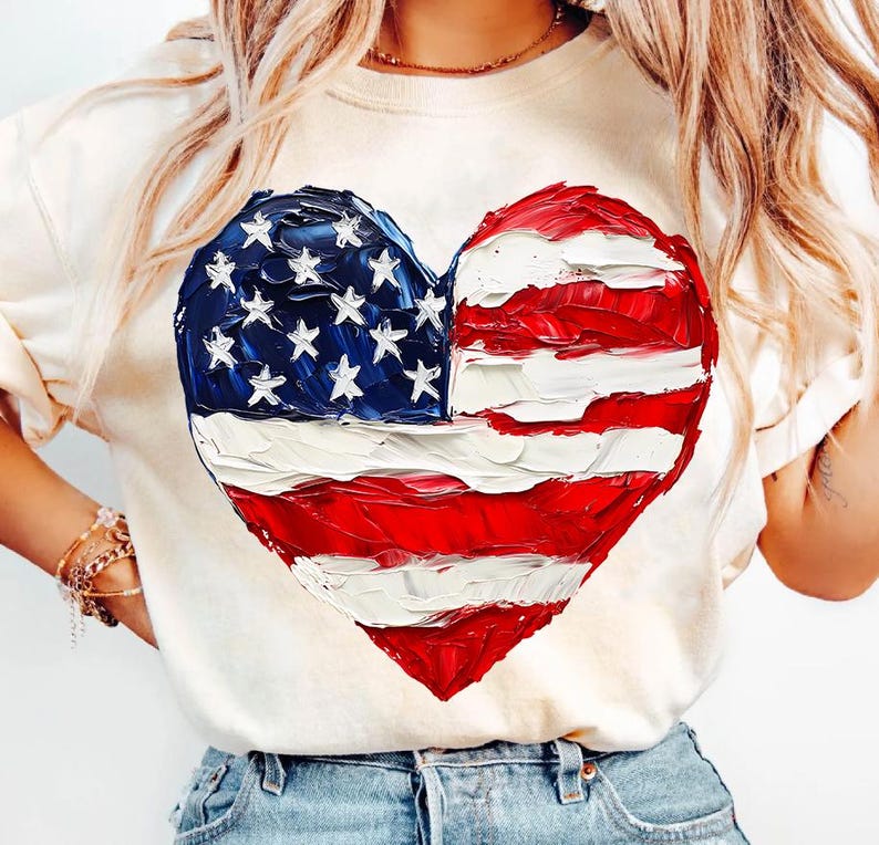 Pu&ograve; includere: Una maglietta bianca con una bandiera americana dipinta a forma di cuore.
