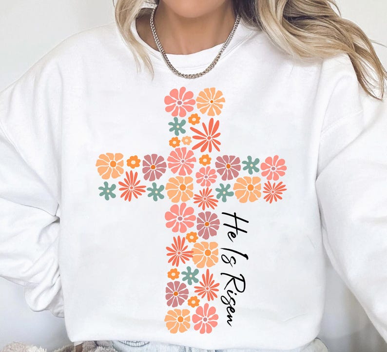 May include: White sweatshirt with a floral cross design and the text "He is Risen".