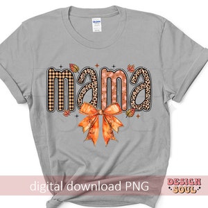 May include: Gray t-shirt with the word "mama" in a fall-themed design. The word is made up of different patterns, including plaid, leopard print, and floral. A large orange bow is below the word.