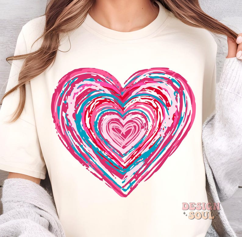 Pu&ograve; includere: Una maglietta bianca con un grande disegno a forma di cuore rosa, rosso e blu. Il cuore &egrave; composto da cerchi concentrici di colore, creando un effetto vorticoso.