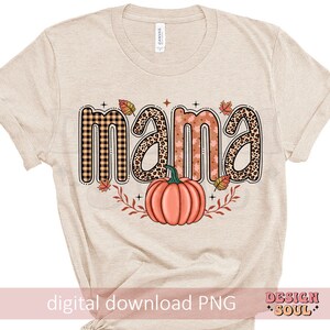 May include: A beige t-shirt with the word "mama" in a fall-themed font with a pumpkin and leaves. The text is in a variety of patterns including plaid, leopard print, and floral.