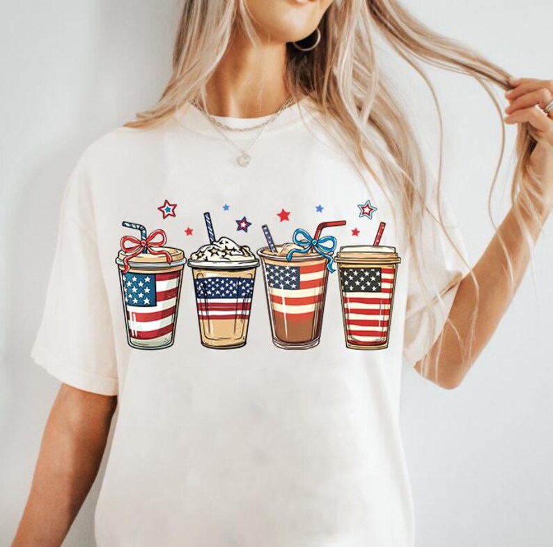 May include: White t-shirt with a graphic of four iced coffee cups decorated with the American flag.