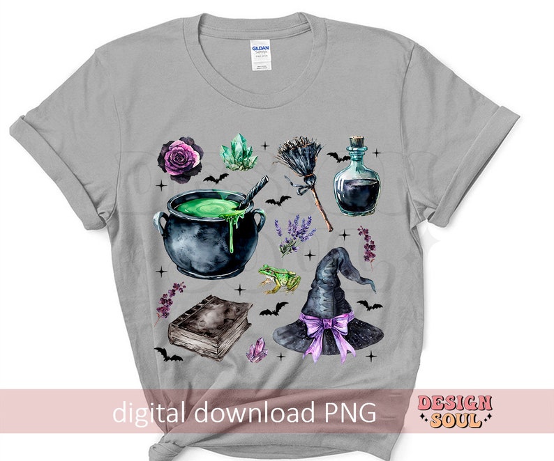 May include: A gray t-shirt with a watercolor design of a witch's hat, cauldron, potion bottle, frog, and other magical elements. The design is in shades of purple, green, and black.