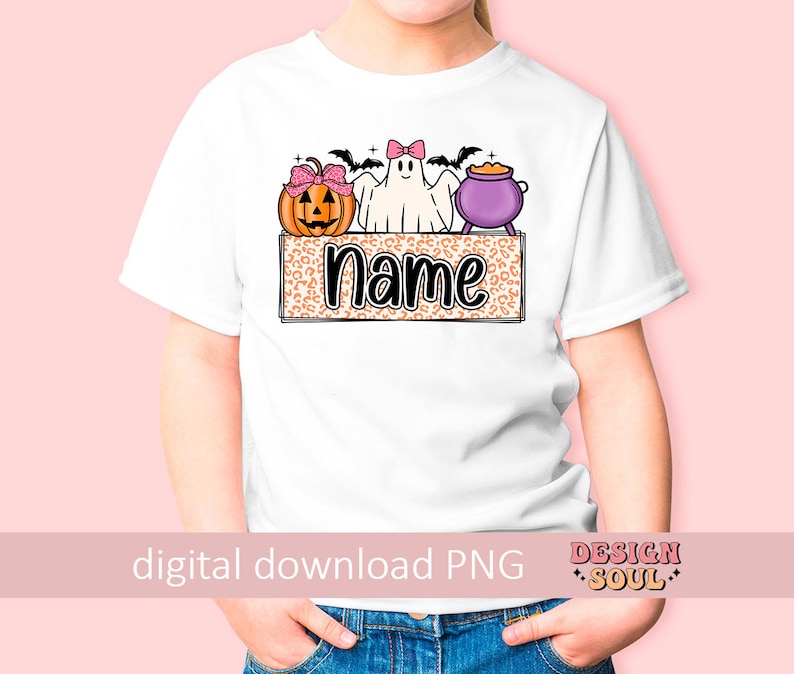May include: A white t-shirt with a Halloween-themed design featuring a ghost, pumpkin, and cauldron. The design is on a leopard print background with the word "Name" in black text.