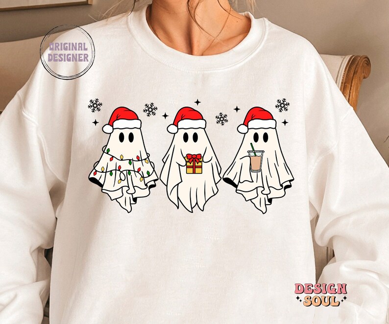 May include: White sweatshirt with a Christmas-themed design featuring three ghosts wearing Santa hats. The ghosts are holding a gift, a cup of coffee, and Christmas lights.