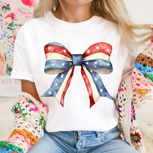K&ouml;nnte beinhalten: Wei&szlig;es T-Shirt mit einer rot-wei&szlig;-blauen Schleife mit Sternen darauf.